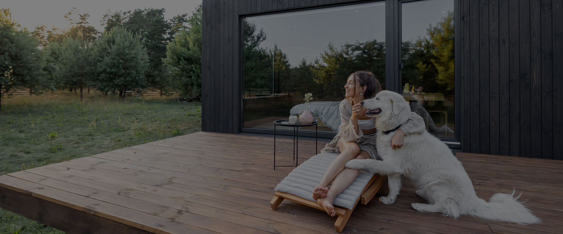 Eine Frau und ein Hund sitzen auf einer Holterrasse