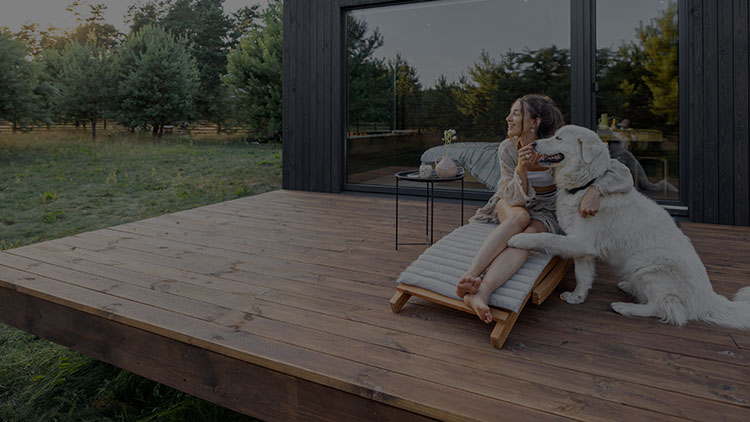 EIne Frau und ein Hund sitzen auf einer Holterrasse