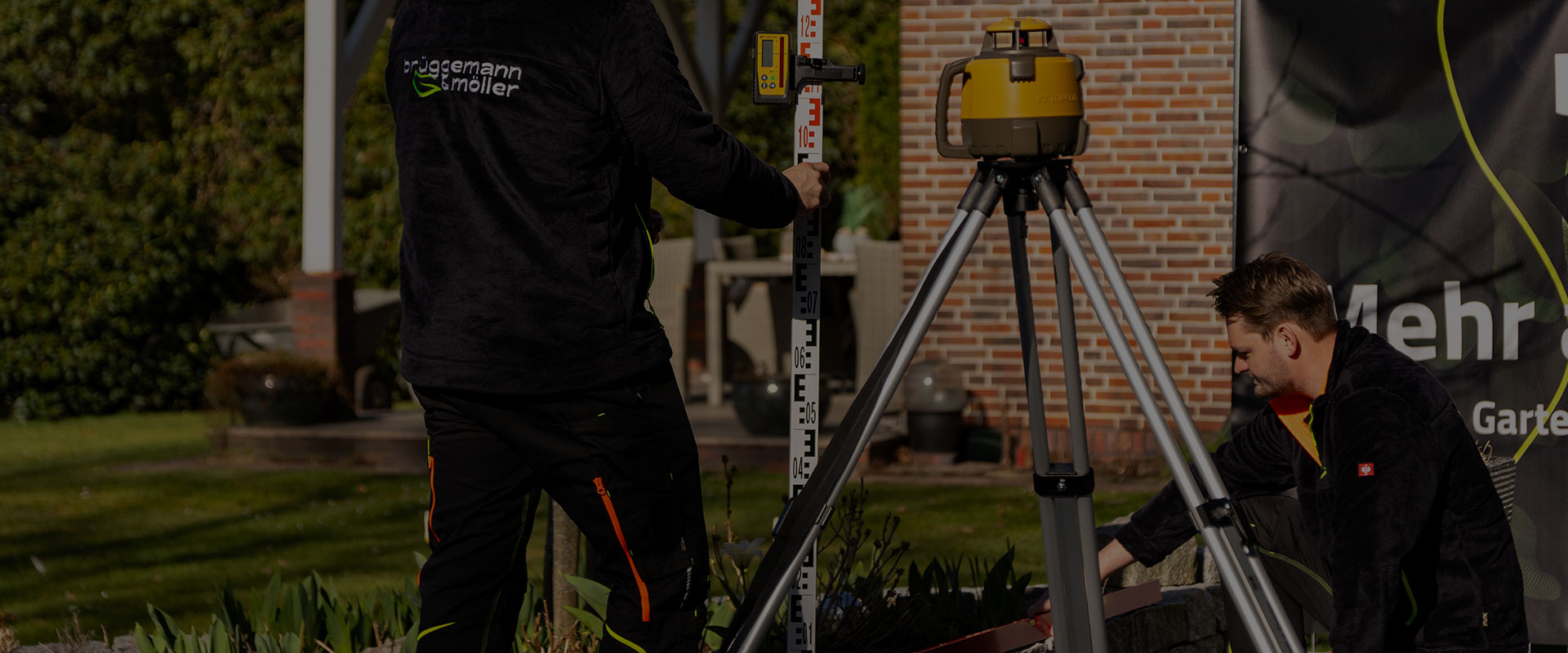 Mann hockt vor einer Mauer und hält eine Wasserwaage an